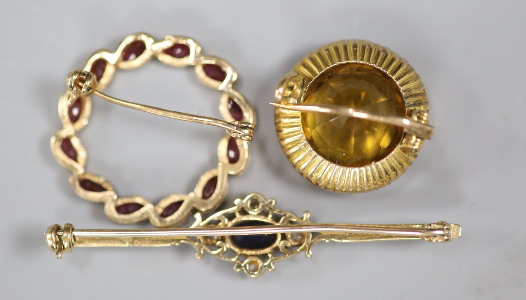 A 9ct gold sapphire and diamond bar brooch, a 14ct and ruby wreath brooch and a yellow tourmaline and seed pearl cluster brooch (3)